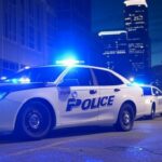 Cena de rua em Minneapolis com viaturas do ICE e fita de cena de crime, representando incidente policial.