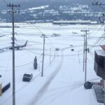 Tempestade de inverno no sul do Brasil com neve, postes caídos e aeroporto parado, representando paralisação por falta de energia e voos cancelados.