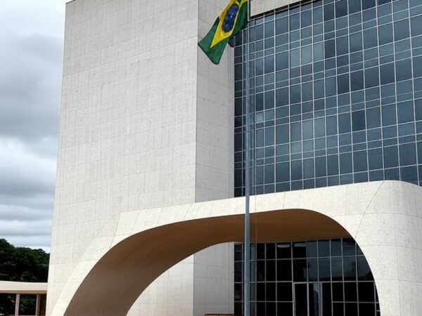 Edifício do Tribunal de Justiça em Brasília com bandeira a meio mastro, simbolizando luto pela morte de desembargador.