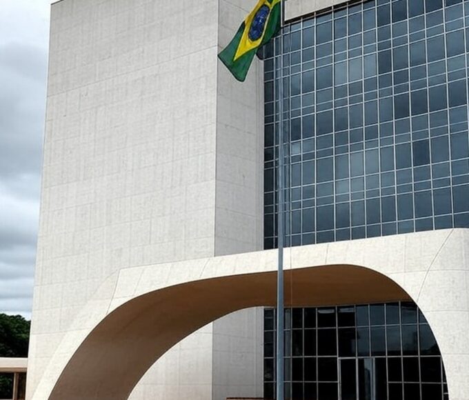 Edifício do Tribunal de Justiça em Brasília com bandeira a meio mastro, simbolizando luto pela morte de desembargador.