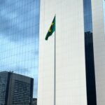 Fachada do Tribunal de Justiça do DF em Brasília com bandeiras a meio mastro, simbolizando luto pela morte de desembargador.