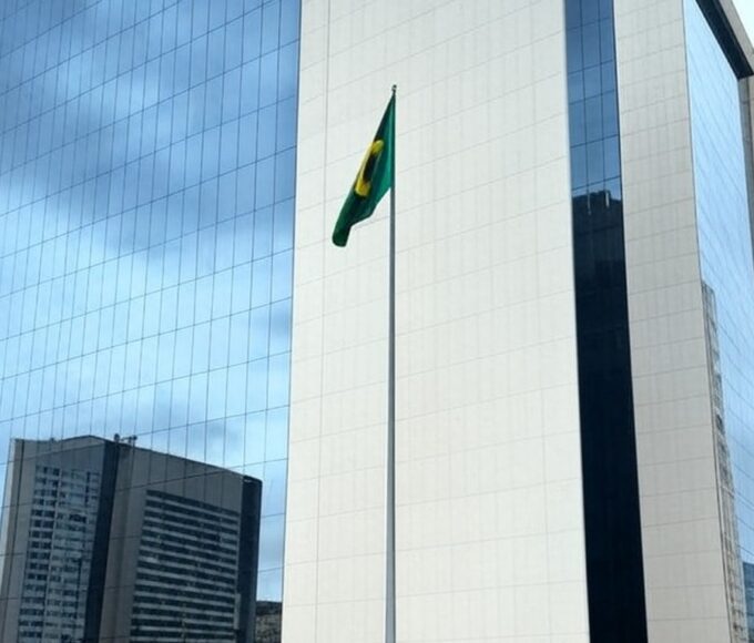 Fachada do Tribunal de Justiça do DF em Brasília com bandeiras a meio mastro, simbolizando luto pela morte de desembargador.