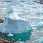 Paisagem glacial da Groenlândia com icebergs e bandeiras simbólicas, representando ameaças e negociações diplomáticas.