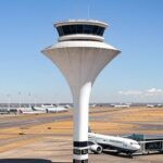 Vista ampla do Aeroporto de Brasília, destacando pontualidade global em segundo lugar, com pista e torre de controle.
