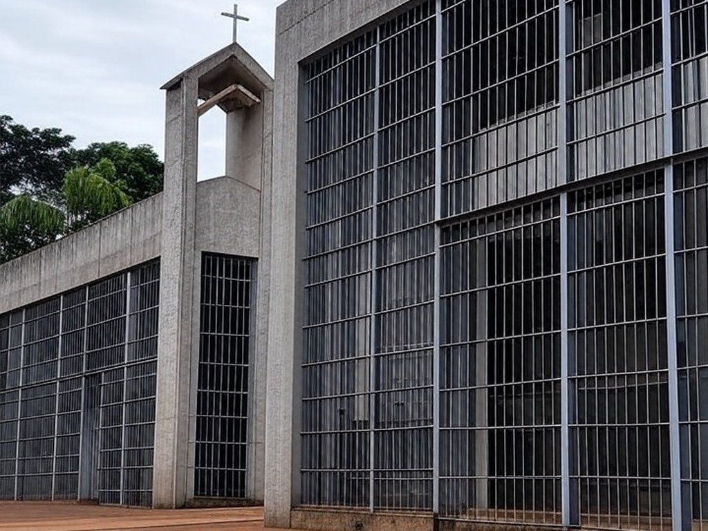 Penitenciária brasileira com capela religiosa ao fundo, representando pedido por assistência espiritual na prisão.