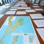 Mesa de conferência com bandeiras da Argentina, EUA e Palestina, documentos de paz para Gaza e mapa da região.