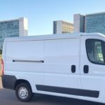 Van de atendimento itinerante da Neoenergia em rua de Brasília, com arquitetura moderna ao fundo.