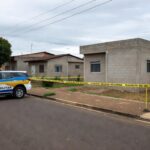 Viatura da Polícia Militar em rua residencial no Gama, Brasília, com fita de isolamento em cena de crime.