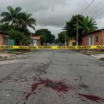 Cena de crime isolada em rua residencial no Gama, com fita policial e marcas no chão, representando denúncia por esfaqueamento.