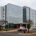 Hospital em Brasília com ambulância na entrada, representando internação por broncopneumonia bacteriana.