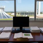Sala de escritório na Secretaria de Educação do DF, com mesa e itens simbólicos de um projeto estudantil em Brasília.