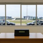 Urna eletrônica em eleição para diretoria do Sinpol-DF, com viaturas da Polícia Civil do DF ao fundo em Brasília.