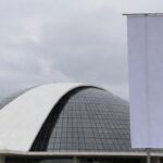 Fachada da Câmara Legislativa do DF com banner vazio, representando homenagem formal a mulheres no setor de seguros sem impacto real.
