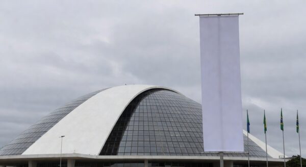 Fachada da Câmara Legislativa do DF com banner vazio, representando homenagem formal a mulheres no setor de seguros sem impacto real.