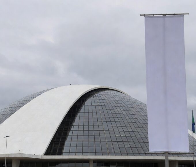 Fachada da Câmara Legislativa do DF com banner vazio, representando homenagem formal a mulheres no setor de seguros sem impacto real.