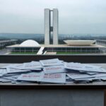 Pilha de currículos rejeitados em escritório de Brasília, simbolizando discriminação etária no emprego.