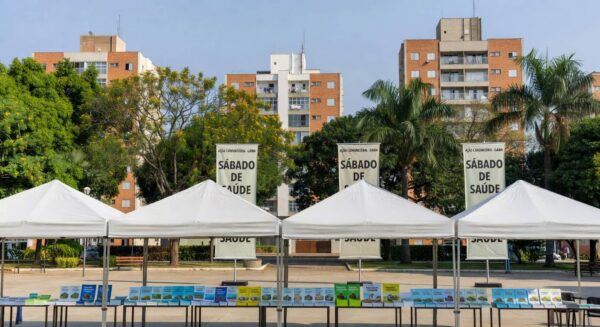 Praça no Gama com tendas para ação comunitária do GDF oferecendo serviços gratuitos.